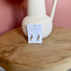 "Boucles d'oreilles créoles dorées en acier inoxydable avec pendentif petite fleur pavée de strass scintillants, présentées par Milë Mila sur un support en bois."