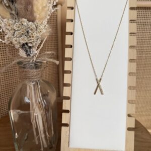Collier fin doré avec pendentif croisé en forme de X, composé d'une barre lisse et d'une barre sertie de strass.