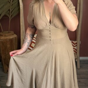 Robe longue beige fluide avec manches courtes bouffantes et décolleté en V portée dans un décor bohème aux tons terracotta